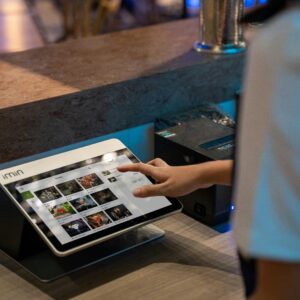 A close-up of a person interacting with a touchscreen in a restaurant setting, showcasing modern technology.